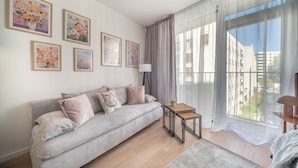 A living room with a sofa, a small table, and a large window with curtains. - Apartment Krochmalna 61 (Warszawa)