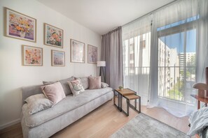 A living room with a sofa, a small table, and a large window with curtains. - Apartment Krochmalna 61 (Warszawa)