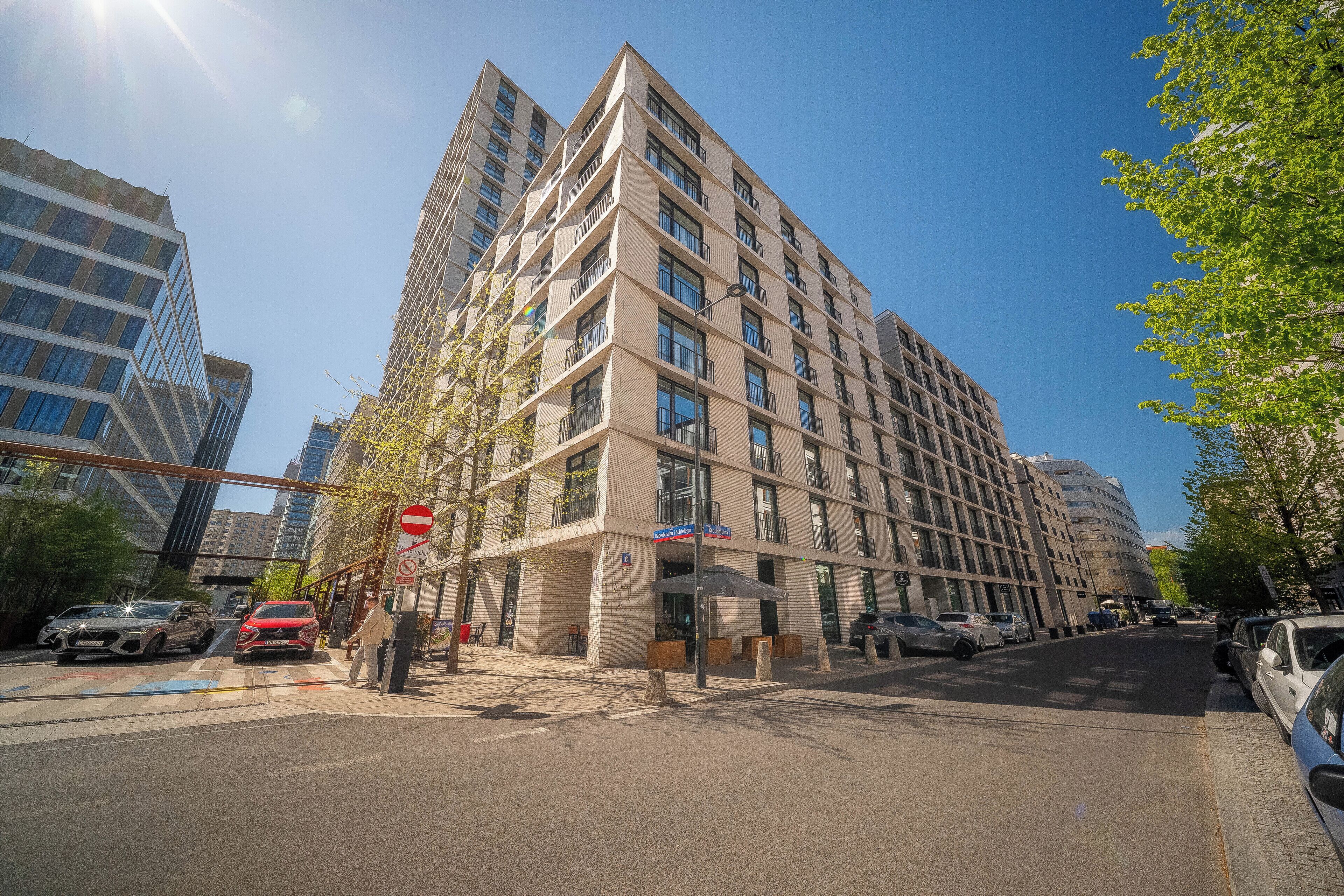Un hôtel à plusieurs étages doté d’une architecture moderne, avec une entrée imposante et un espace de stationnement bien visible.