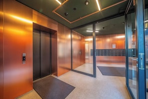 A modern elevator area with metallic walls, a digital display, and a glass door. - Apartment Krochmalna 61 (Warszawa)