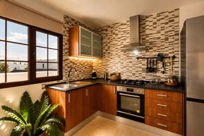 A modern kitchen with wooden cabinets, a stainless steel sink, and a built-in oven. - Casa Carla Terraza BBQ y Jard n Volc Nico (Tinajo)