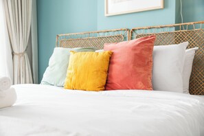 Ein Bett mit weißer Bettwäsche und vier Kissen in verschiedenen Farben.