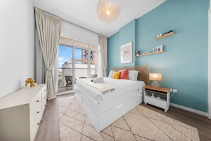 Ein modernes Schlafzimmer mit einem großen Bett, einem Nachttisch, einem Schreibtisch und Blick ins Freie.