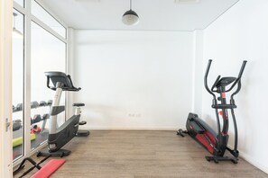 Ein Fitnessraum mit Trainingsgeräten, einem Spiegel und einem Fenster.