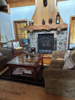A cozy living room with a stone fireplace, wooden beams, and comfortable seating.