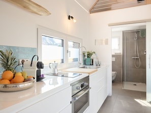 A modern kitchen with a large island, stainless steel appliances, and a view to the outside.