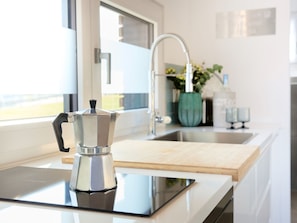 A modern kitchen with a coffee maker on the counter, a sink, and a window.