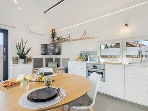 A modern kitchen with a central island, built-in appliances, and a dining area with a round table and chairs.