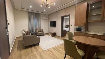 A modern living room with a sofa, chairs, a coffee table, and a TV.