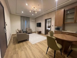 A modern living room with a sofa, chairs, a coffee table, and a TV.