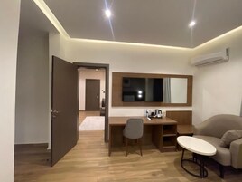 A modern room with a desk, chair, sofa, and a flat-screen TV mounted on the wall.