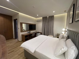 A hotel room with a bed, a desk, a chair, a television, and a wardrobe.