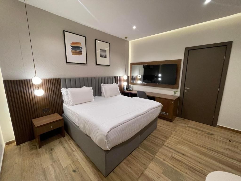 Un dormitorio moderno con una cama grande, mesitas de noche, un escritorio y un armario.