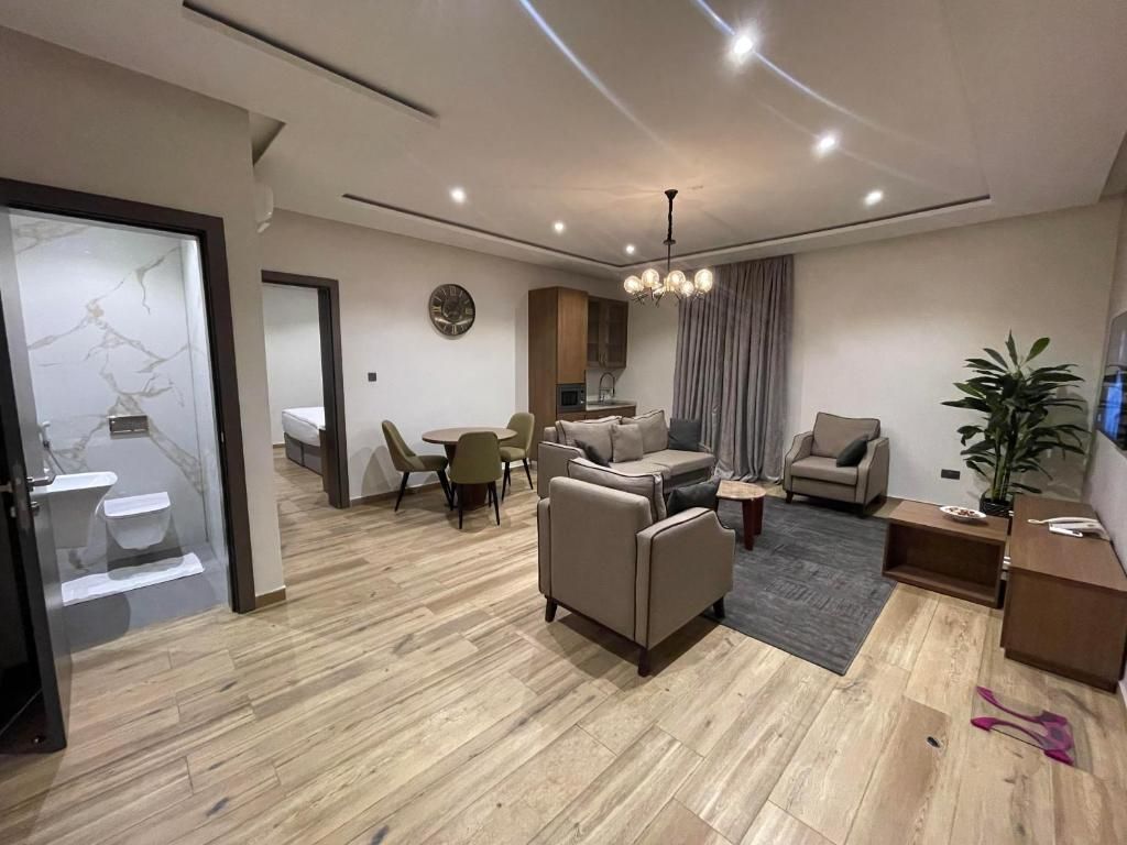 A modern living room with a sofa, chairs, a dining table, and a kitchen area.