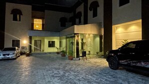 Ein Innenhof mit Pflasterboden, einem Auto und einem Gebäude mit großen Fenstern und einer Tür.