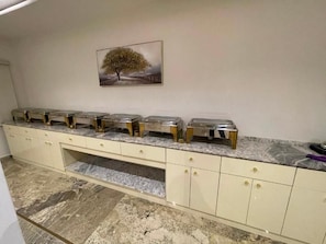 A kitchen with a marble countertop, a sink, and a cabinet with drawers. - Checkinn Hotel And Resort (Jimeta)