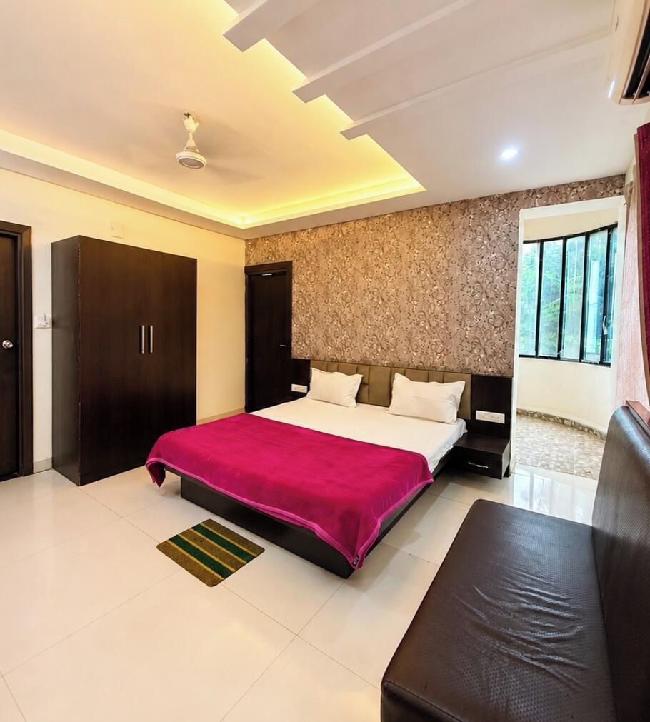 A bedroom with a bed, a bench, a wardrobe, and a window.