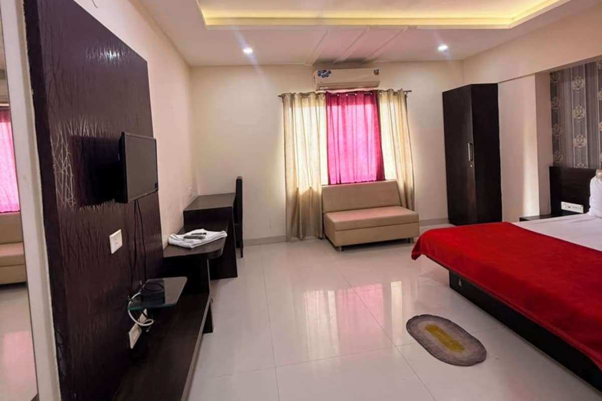 Una habitación de hotel con cama, escritorio, silla, televisor y armario.