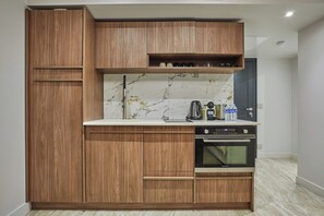 A compact kitchen with wooden cabinets, a marble backsplash, and a built-in oven. - New Apartment Center of Paris/le Marais (Paris)