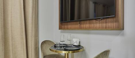 A room with a round table, two chairs, a mirror, and a curtain.