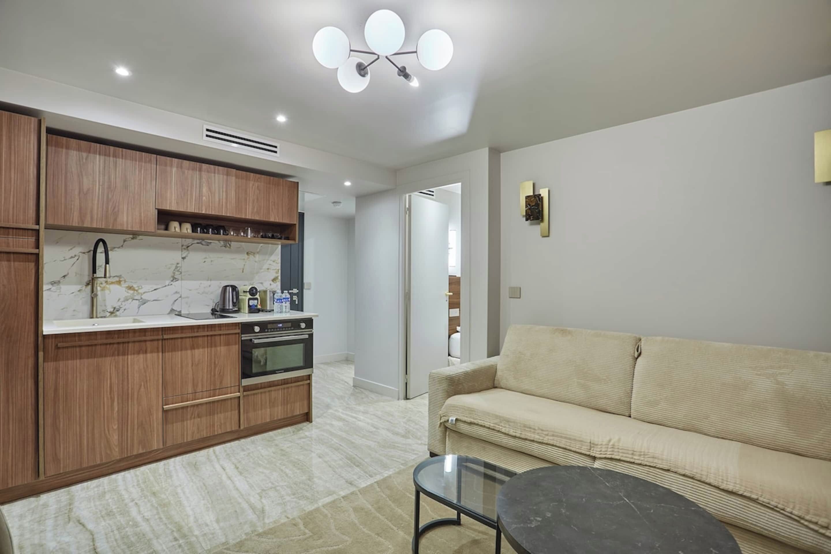 A modern kitchen with wooden cabinets, a marble countertop, and a built-in oven.