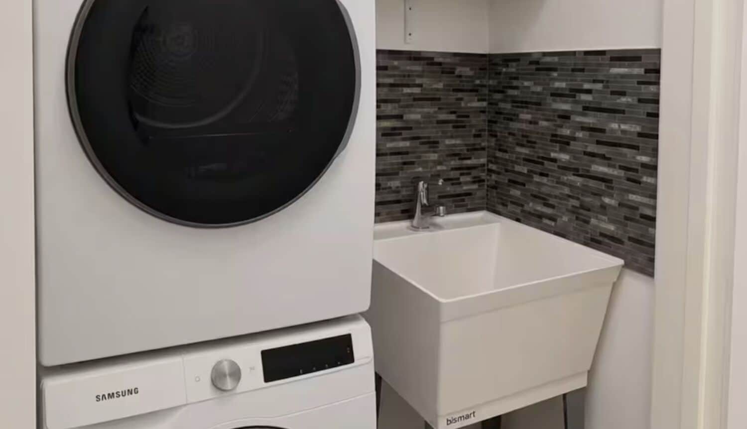 Un área de lavandería compacta con una lavadora Samsung y un lavabo blanco con el logotipo de bismart.