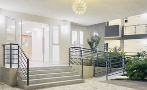 Un interior moderno con una escalera, una araña y vistas al exterior.