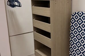Un armario de madera con varios estantes y una barra para colgar.