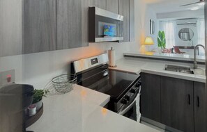 Una cocina moderna con horno integrado, microondas y un amplio ventanal.