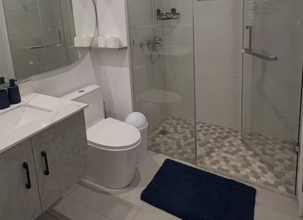 Un baño con inodoro, cabina de ducha y lavamanos.