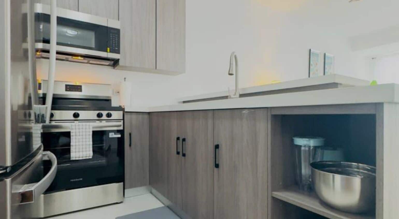 Una cocina moderna con electrodomésticos de acero inoxidable, armarios de madera y horno empotrado.