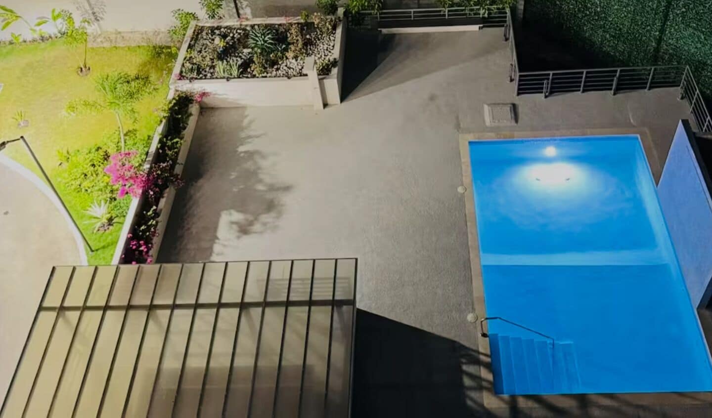 Una piscina en la azotea con vistas despejadas del entorno, incluyendo un jardín y una escalera.