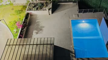 Una piscina en la azotea con vistas despejadas del entorno, incluyendo un jardín y una escalera.