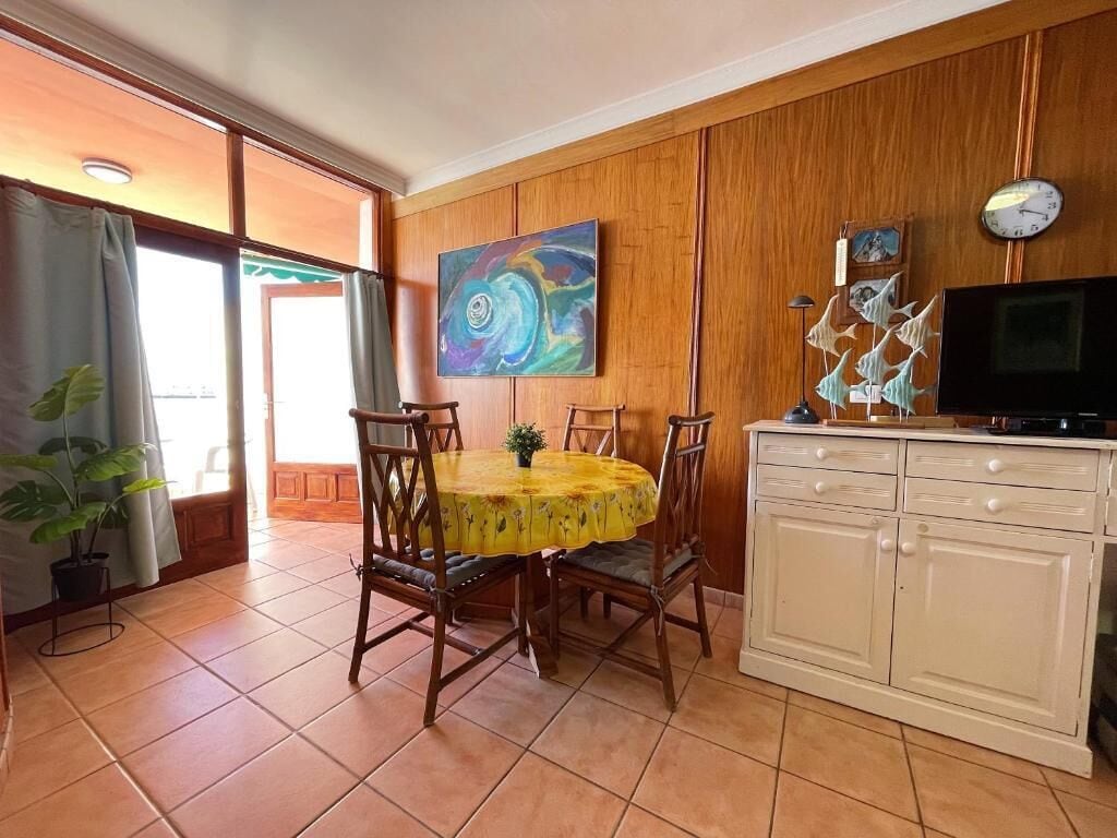 A dining area with a round table, chairs, and a cabinet with a television.