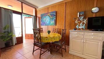 Un comedor con una mesa redonda, sillas y un mueble con televisión.