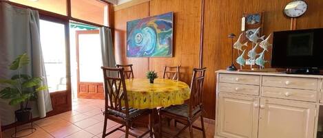 A dining area with a round table, chairs, and a cabinet with a television.