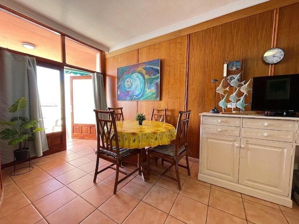 A dining area with a round table, chairs, and a cabinet with a television. - Apartment Cristianmar (Arona)