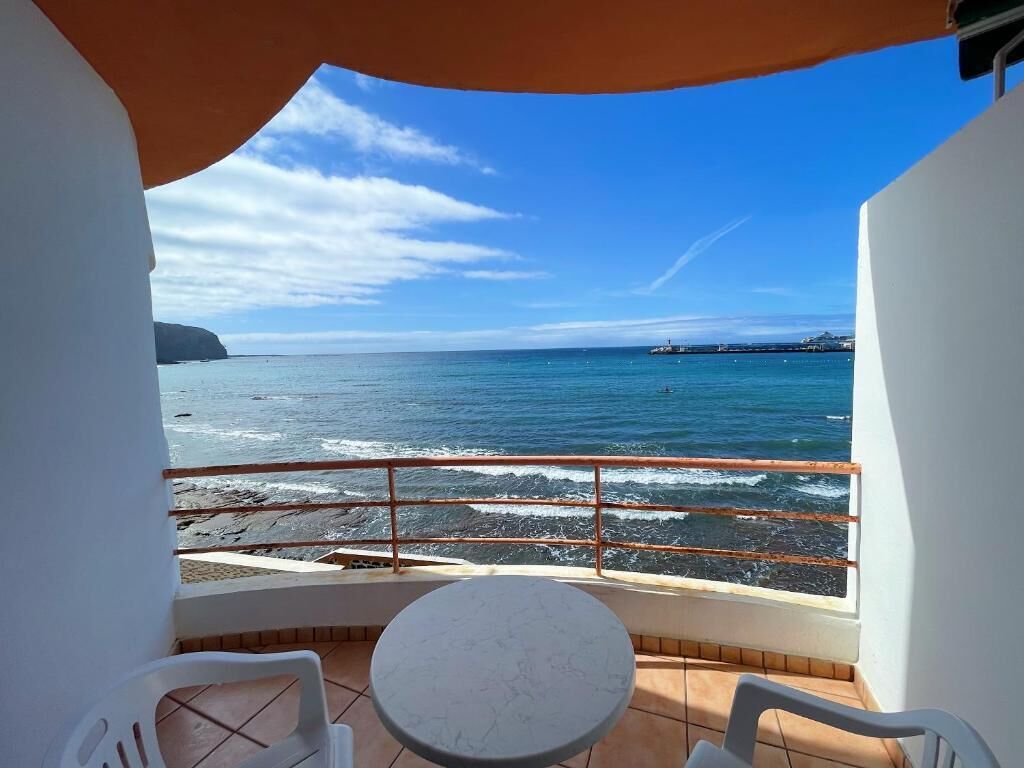 Un balcon avec vue sur la mer, une table et deux chaises.