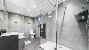 Ein modernes Badezimmer mit Duschkabine aus Glas, einer weißen Toilette und einem Waschtisch.
