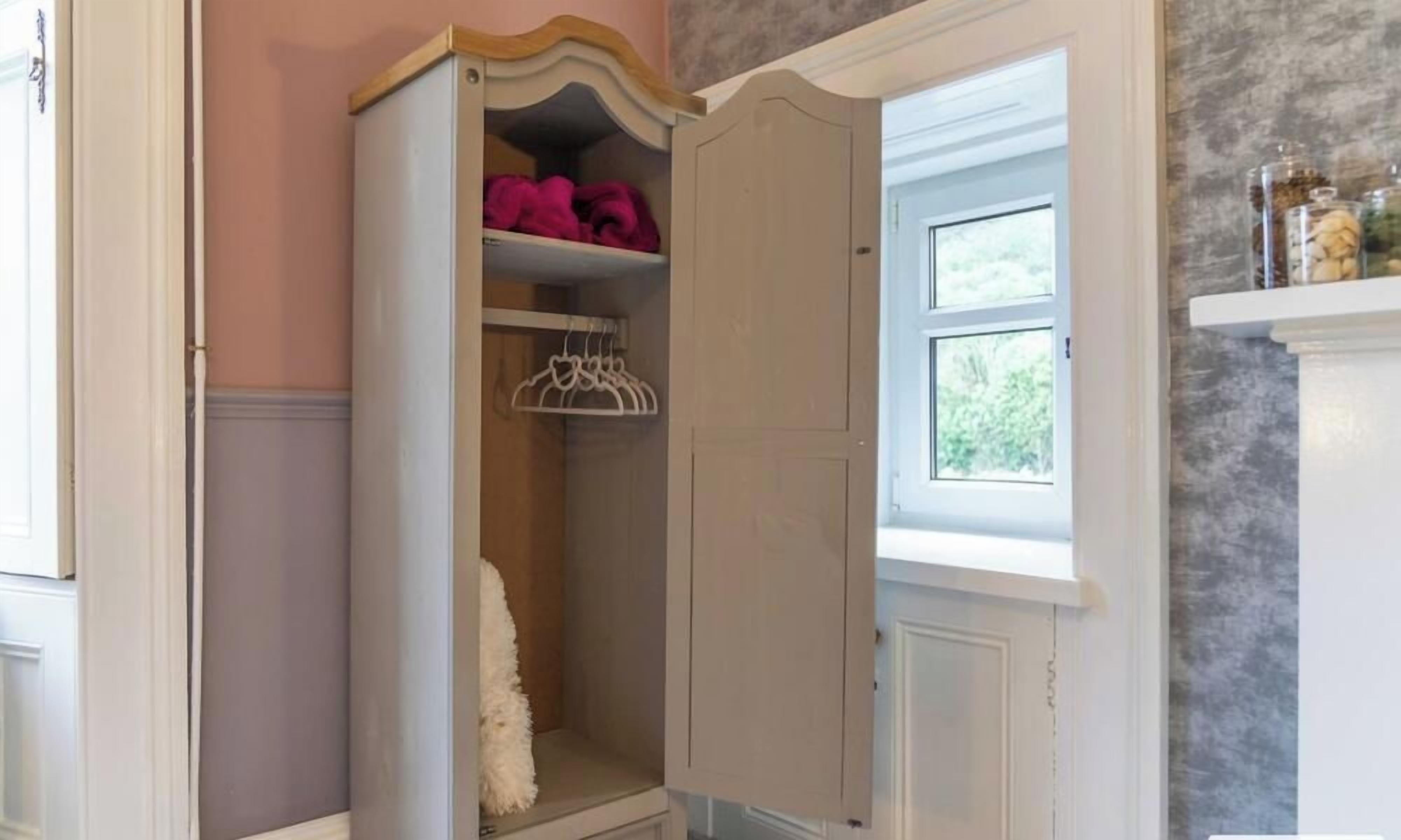 Une pièce avec une armoire, une fenêtre et une étagère où sont posés des bocaux.