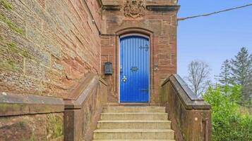 Un bâtiment en pierre avec une porte bleue et un escalier en pierre menant à l’entrée.