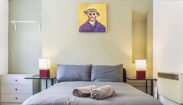 A hotel room with a bed, two bedside tables with lamps, a nightstand, and a painting on the wall. - Flora`s Flat 5 - Near Nottingham Centre! (Nottingham)