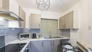 A compact kitchen with a microwave, kettle, and a sink.
