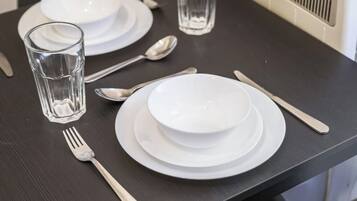 A table set with white plates, a bowl, a glass, a fork, and a spoon.