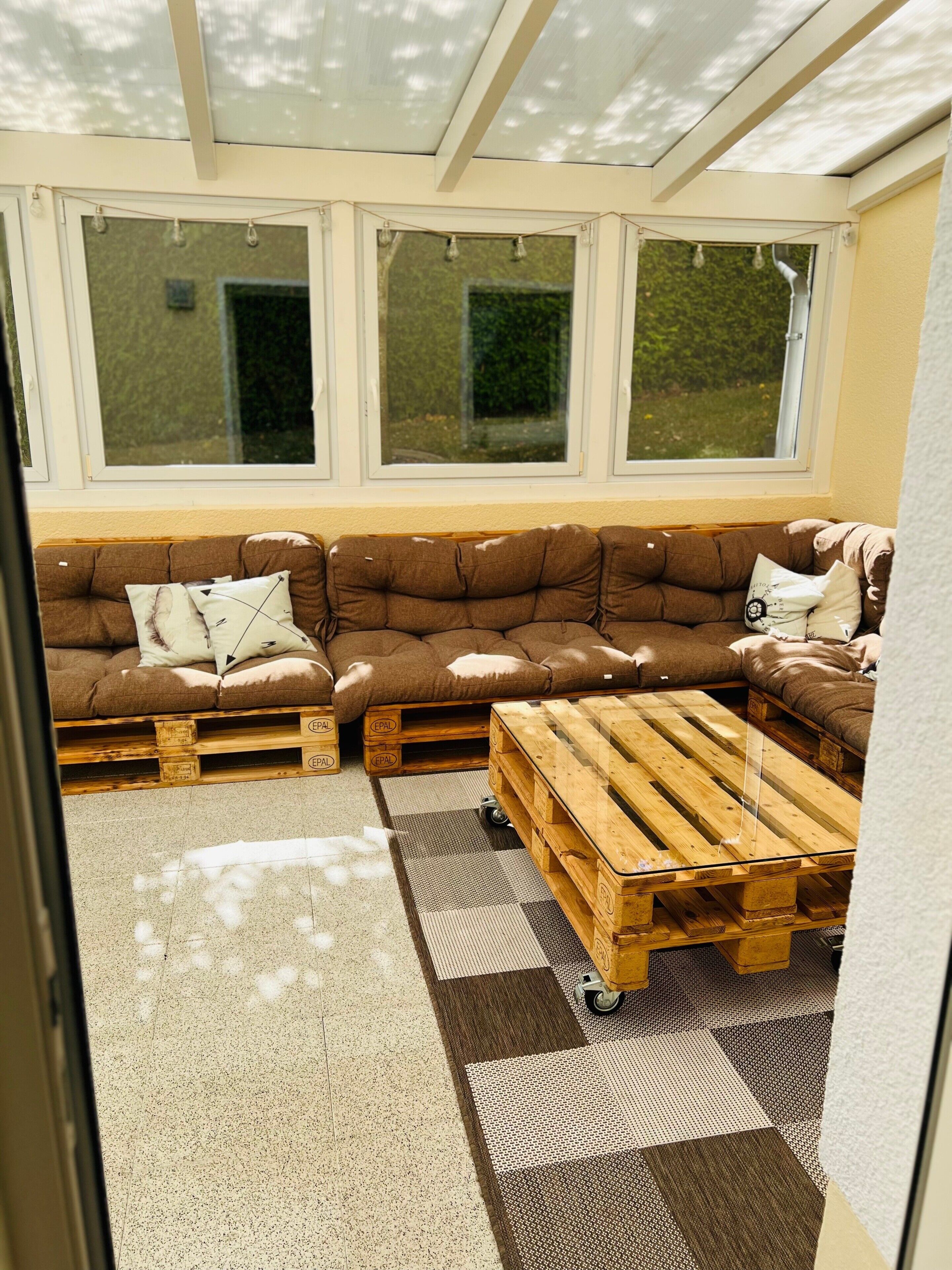 Ein gemütlicher Sitzbereich mit braunem Sofa und einem Holztisch, mit Blick durch große Fenster.