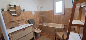 A bathroom with a bathtub, a sink, a mirror, and a shower. - A family home in Brittany, a ten-minute walk from Paimpol and its harbor (Ploubazlanec)