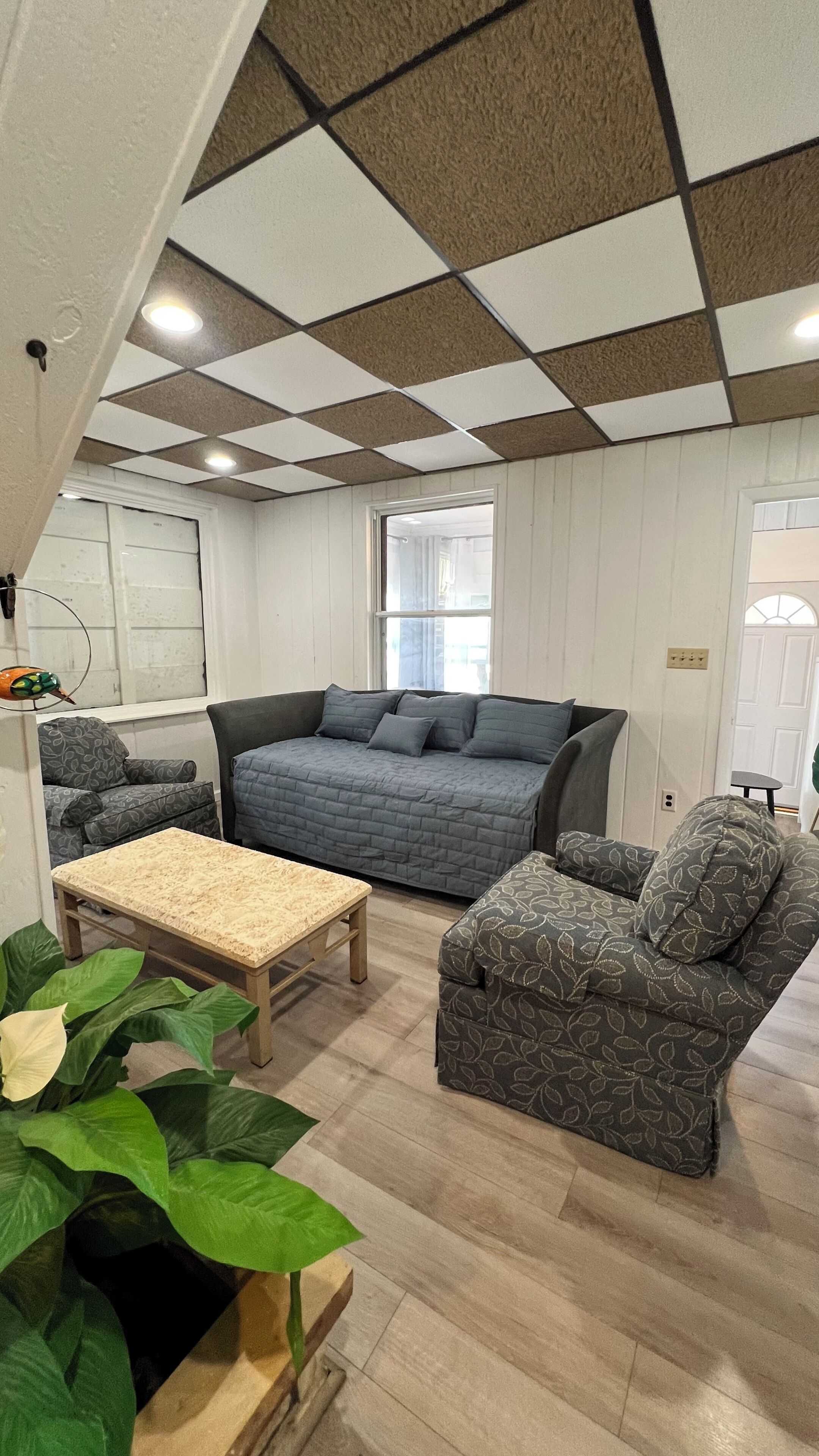 Un salon chaleureux avec un grand canapé, un fauteuil plus petit et une table basse en bois.