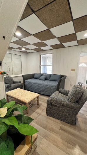 Ein gemütliches Wohnzimmer mit einer großen Couch, einem kleinen Sessel und einem Holztisch.