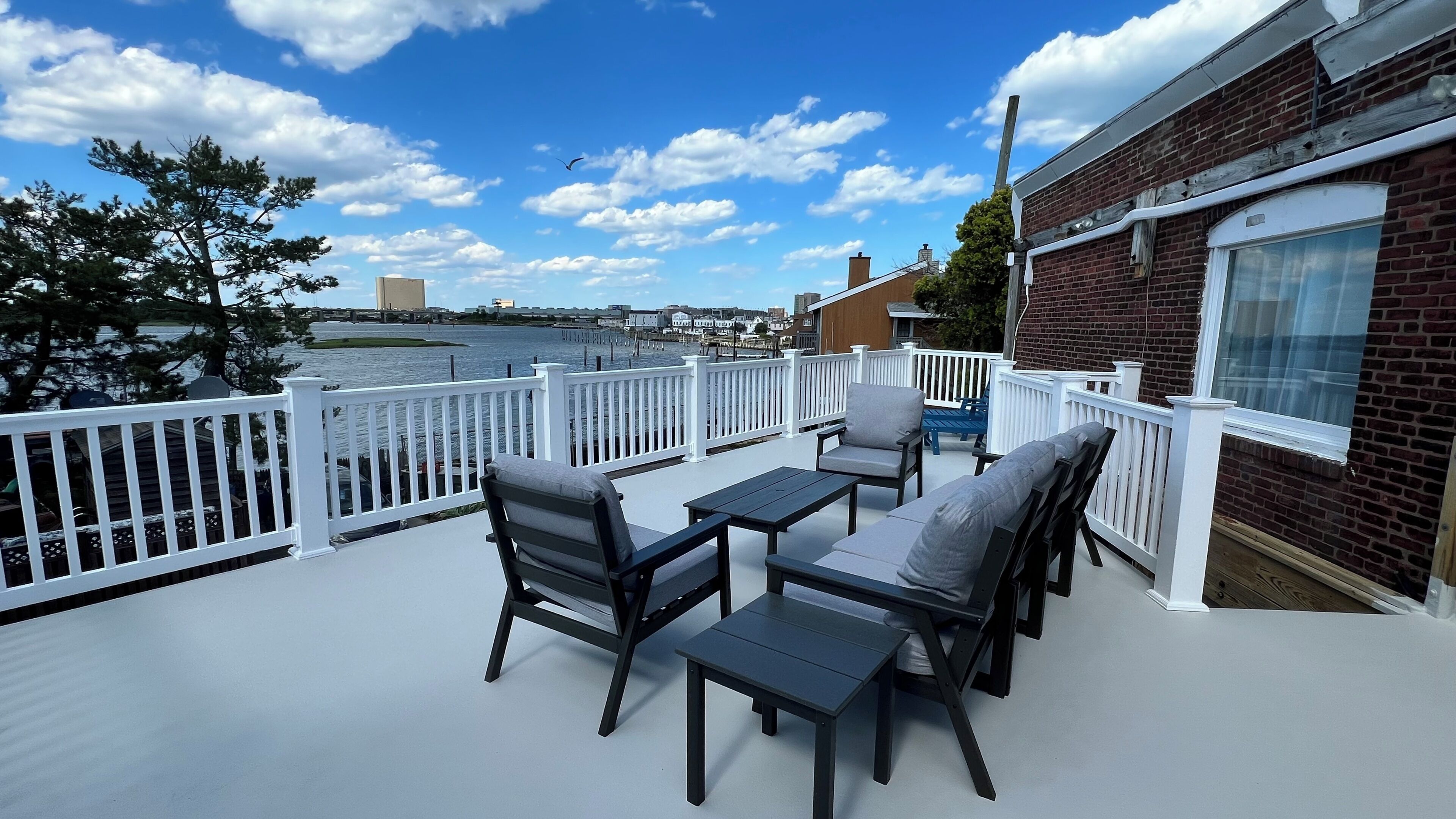 A deck with outdoor furniture overlooking a body of water.