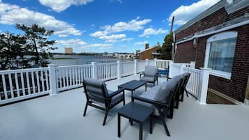 A deck with outdoor furniture overlooking a body of water.